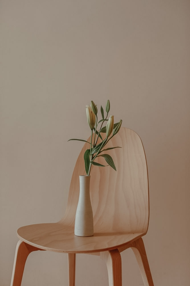 Minimal aesthtetic, wood chair with a beautiful flower.