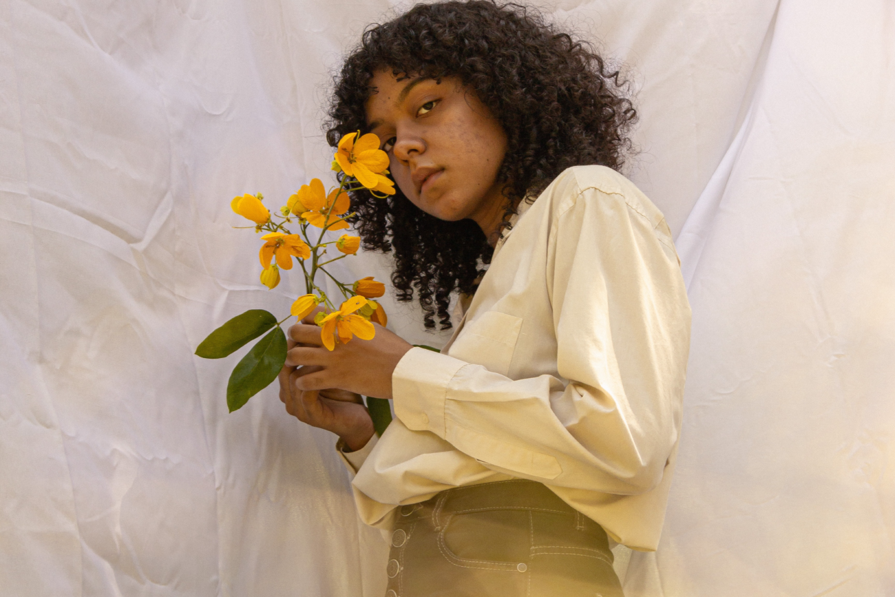 Black Women with curly hair holding a flower.